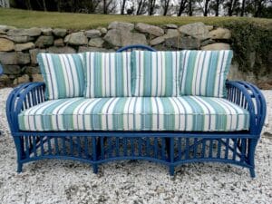 Wicker sofa painted blue as part of a three piece set. Cushion covers upholstered in a Perennials Beachcomber Stripe outdoor fabric. All new antimicrobial seat foam wrapped in dacron batting. All new weatherproof back pillow inserts. Upholstered by Cape Cod Upholstery Shop | Located in South Dennis, MA 02660