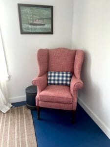 Decorative pillow in a blue and white plaid on a wing chair with a solid raspberry upholstery fabric | Upholstered by Cape Cod Upholstery Shop | Located in South Dennis, MA 02660