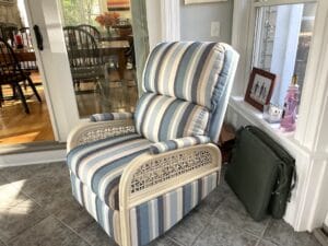 Rattan swivel recliner shown in the clients three season room. Upholstered in a Sunbrella Scope Cape stripe fabric | Upholstered by Cape Cod Upholstery Shop | Located in South Dennis, MA 02660